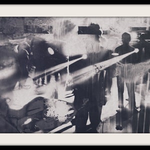 Könnte beinhalten: Ein abstraktes Schwarzweißbild von zwei Figuren, die in einem Scheinwerferlicht stehen. Die Figuren sind teilweise von einem verschwommenen Hintergrund verdeckt.