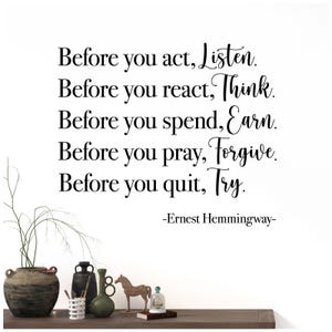 Puede incluir: Fondo blanco con la cita "Antes de actuar, escucha. Antes de reaccionar, piensa. Antes de gastar, gana. Antes de rezar, perdona. Antes de rendirte, inténtalo." de Ernest Hemingway. Objetos decorativos sobre una estantería de madera.