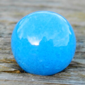 Puede incluir: Un mármol redondo y liso de color azul claro con un patrón de mármol.