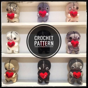 May include: A collection of handmade crochet dolls, each holding a red heart. The dolls are in various colors, including beige, gray, and black, with stitched details. The image includes the text "CROCHET PATTERN" in a circular design.