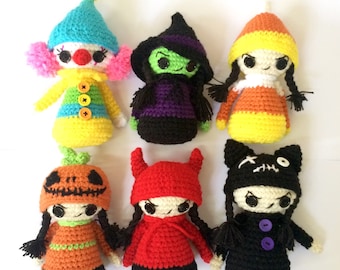 May include: Six crocheted Halloween characters, including a clown, witch, candy corn, pumpkin, devil, and cat. Each character is handmade and features unique details, such as buttons, yarn colors, and facial expressions.