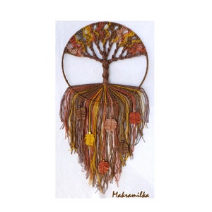 May include: A macrame wall hanging in the shape of a tree with brown, orange, and yellow yarn. The tree has a circular base and is decorated with small, square-shaped leaves.