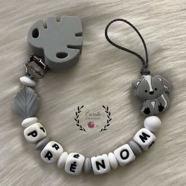 Attache tétine personnalisé entièrement en silicone (lettre prénom, clip motif, perle ronde lentille) Moufette putois, gris clair et blanc