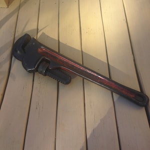 May include: A black and red pipe wrench with a black handle and a red painted body.