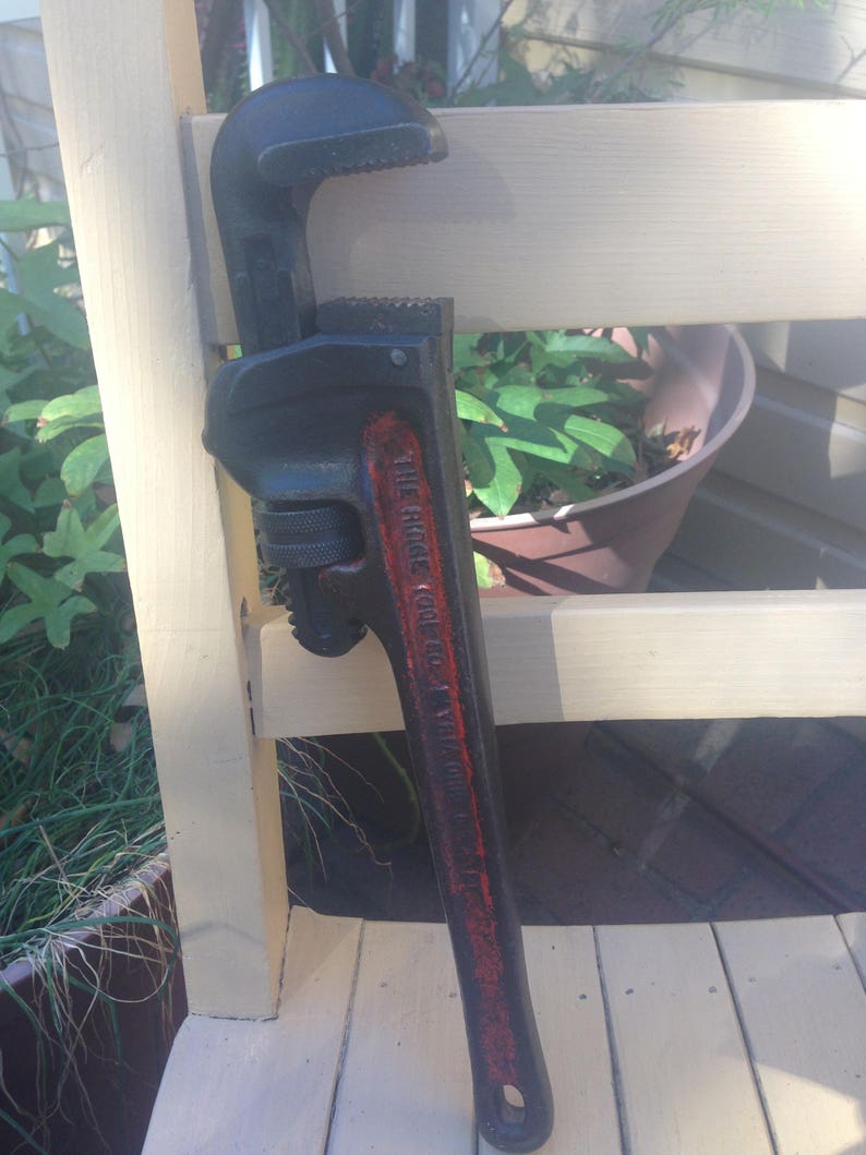 May include: A black and red pipe wrench with the text "THE RIDGE TOOL CO. "THE RIDGE" printed on the side.