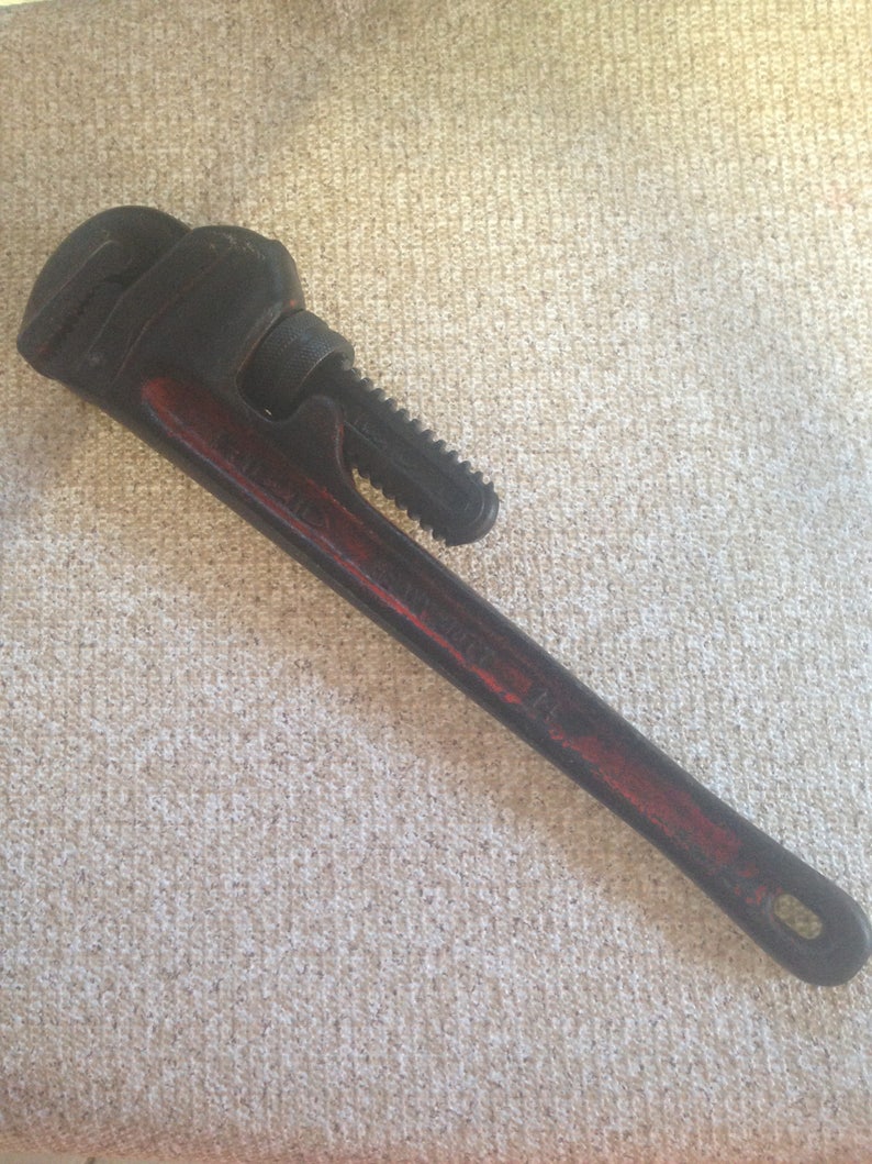 May include: A black and red pipe wrench with a serrated jaw and a red handle.