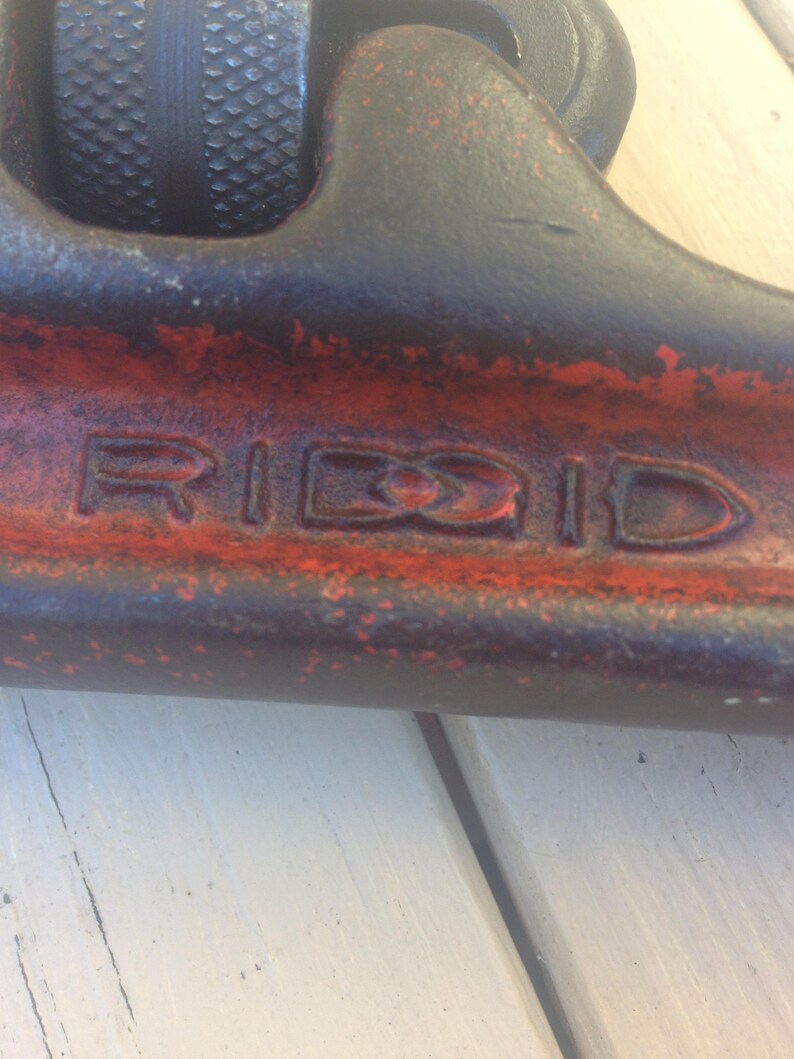 May include: Close-up of a red and black pipe wrench with the word "RIDGID" embossed on the side.