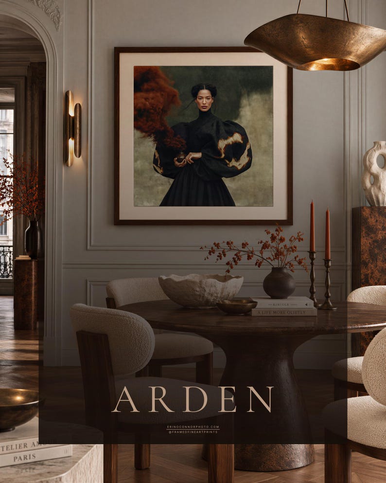 Peut inclure: Une impression d'art murale carr&eacute;e encadr&eacute;e intitul&eacute;e ARDEN repr&eacute;sentant le portrait d'une personne v&ecirc;tue d'un v&ecirc;tement noir &agrave; col montant et manches volumineuses, tenant un petit objet d&eacute;gageant un nuage de fum&eacute;e rouge sombre sur fond textur&eacute;.