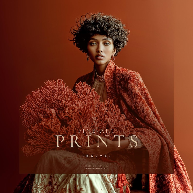 Kavya fine art portrait of woman seated with red coral against burnt orange background in rust patterned wrap and ivory dress