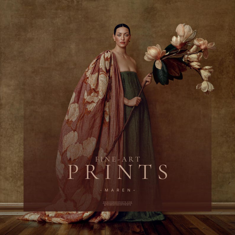 Maren fine art portrait of a pregnant woman in a dark green dress with a sweeping dusty rose floral drape holding an oversized magnolia branch.