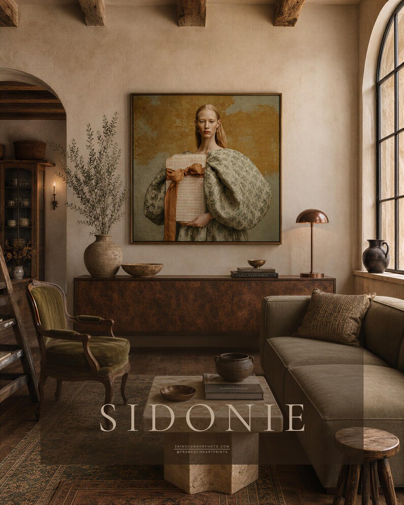 Large framed Sidonie portrait above a burled wood credenza in a warm European-inspired living room with plaster walls, olive velvet, stone, wood, and brass accents.