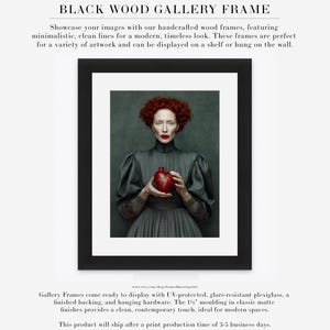 Fine art portrait of Cinder framed in black wood with white matte, ideal for bold modern interiors, featuring a woman with red curls holding a red anatomical heart vessel.
