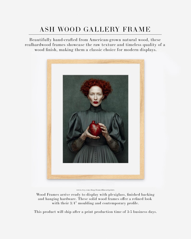 Cinder fine art print framed in a light ash wood gallery frame with white matte, featuring a red-haired woman in a dark dress holding a heart-shaped vessel on a deep green backdrop.