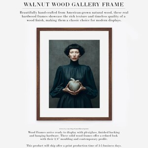Sable framed in a walnut wood gallery frame with white matte, featuring a woman holding a kintsugi heart in a dark high-collar dress.