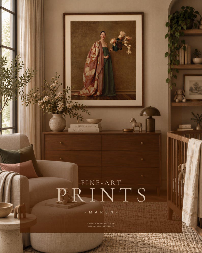 Large framed Maren portrait displayed above a walnut dresser in a contemporary nursery with cream linen seating, warm neutral walls, plants, and soft natural textures.