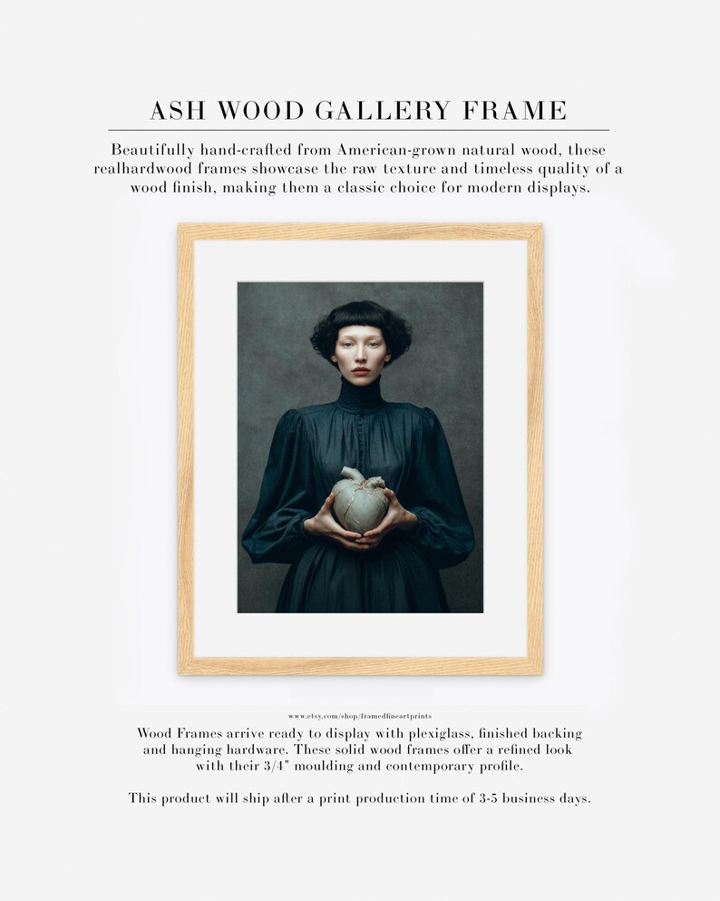 Sable framed in an ash wood gallery frame with white matte, featuring a dark-haired woman holding a gold-repaired heart on a moody green backdrop.
