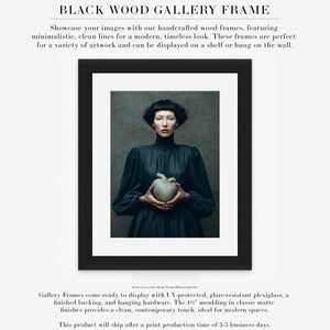 Fine art portrait of Sable framed in a black gallery frame with matte, showing a woman holding a symbolic ceramic heart against a painterly background.