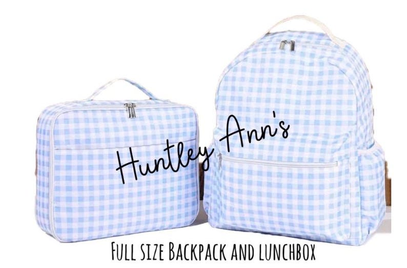 May include: A light blue and white gingham-patterned backpack and matching lunchbox. The backpack has a front pocket and side pockets. The lunchbox has a handle and a zipper closure. The text "Huntley Ann's" is on both items. The text "FULL SIZE BACKPACK AND LUNCHBOX" is at the bottom.