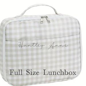 May include: A full-size lunchbox with a light gray and white gingham pattern. The lunchbox has a handle, a zippered closure, and a front pocket. The text "Huntley Ann's" and "Full Size Lunchbox" are printed on the front.