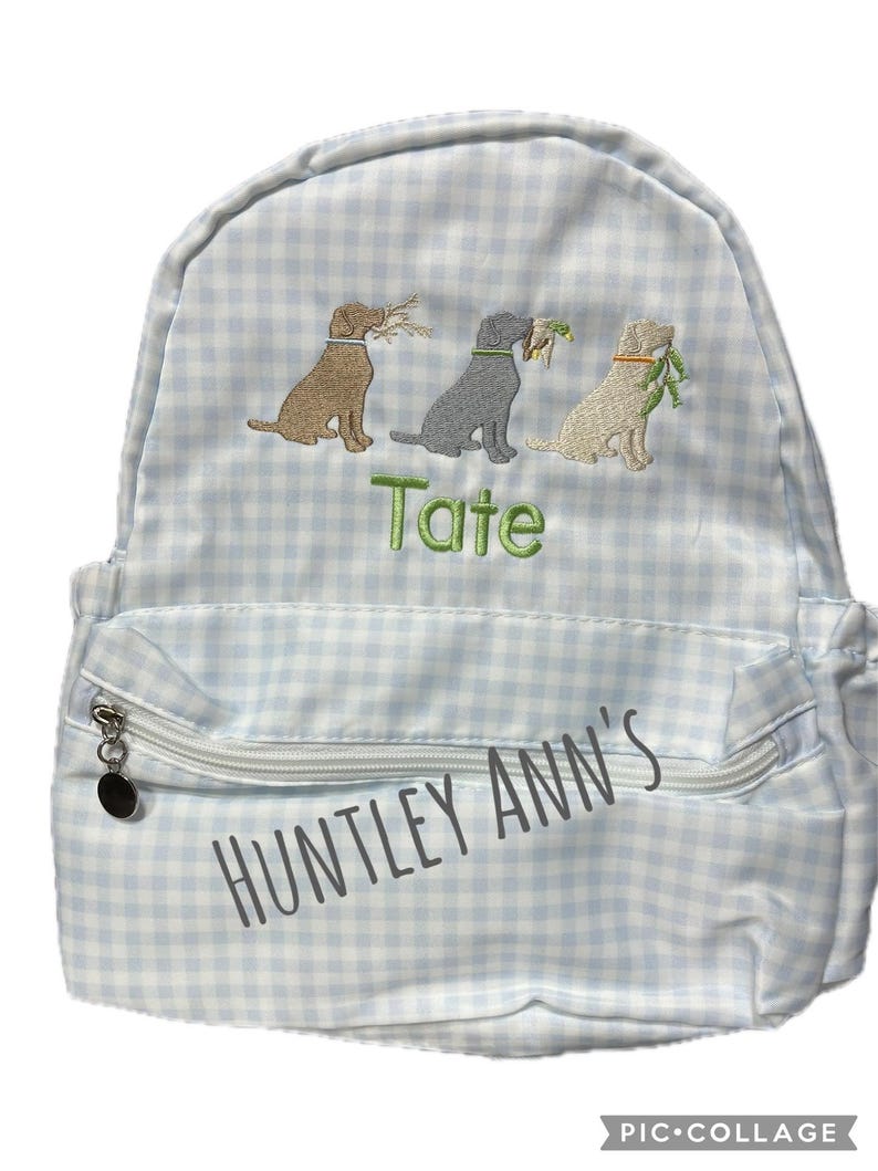 May include: A light blue and white gingham backpack with three embroidered dogs carrying foliage. The backpack has a front zippered pocket and the text "Huntley Ann's" and "Tate".