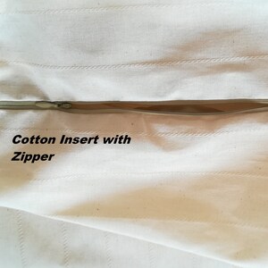 May include: Close-up of a white cotton fabric with a zipper. The fabric has a subtle striped pattern and the text "Cotton Insert with Zipper" is visible.
