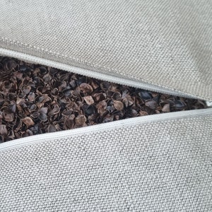 Op de afbeelding: Een beige kussensloop met een rits is open om een ​​bruine boekweitvulling te laten zien.