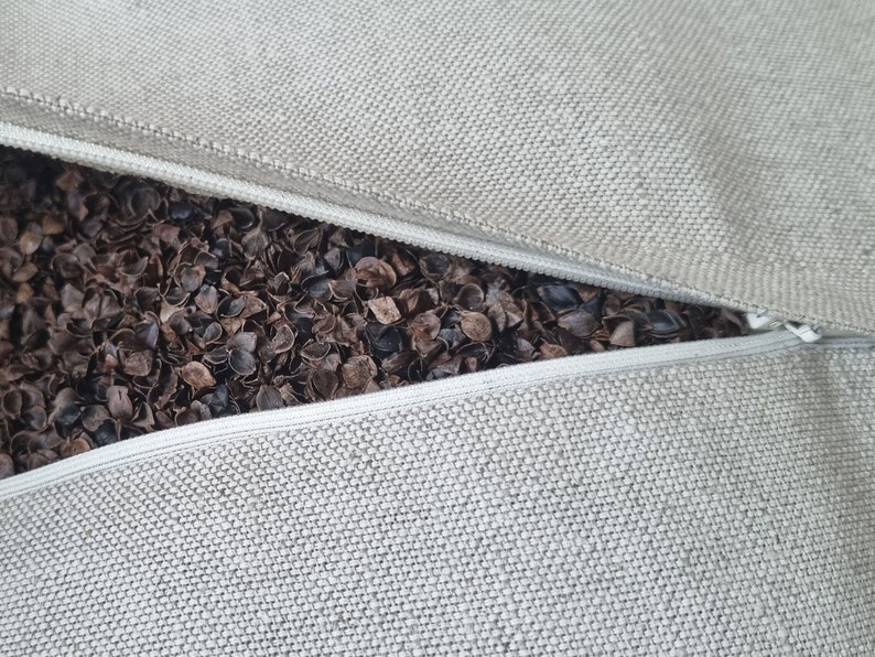 Op de afbeelding: Een beige kussensloop met een rits is open om een ​​bruine boekweitvulling te laten zien.