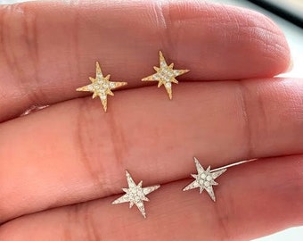 Op de afbeelding: Twee paar stervormige oorbellen met een diamant-achtige glans. Het ene paar is goud en het andere is zilver.