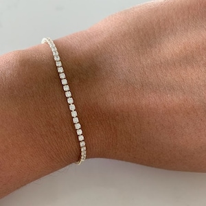 Op de afbeelding: Een gouden tennisarmband met kleine ronde diamanten.