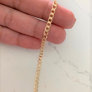 Puede incluir: Un collar de cadena curb de oro con un diseño clásico. La cadena está hecha de oro macizo y tiene un acabado liso y pulido.
