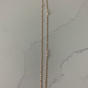 May include: A gold chain necklace with a delicate, rope-like design. The chain is approximately 18 inches long.