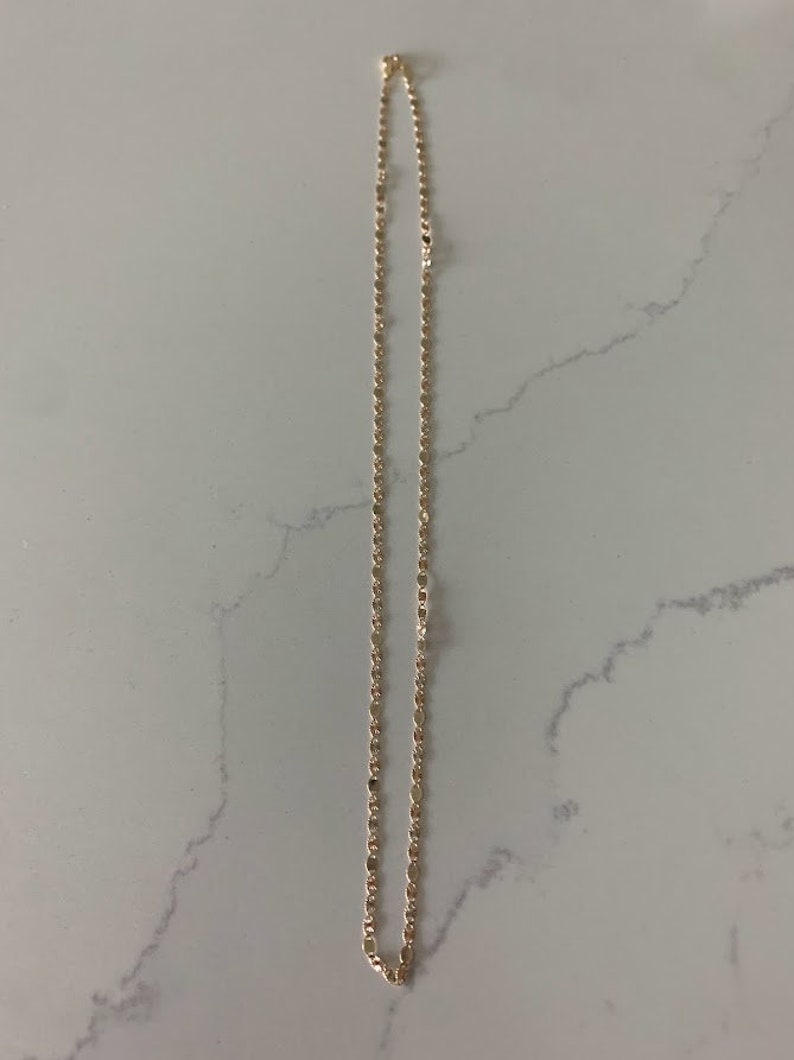 May include: A gold chain necklace with a delicate, rope-like design. The chain is approximately 18 inches long.