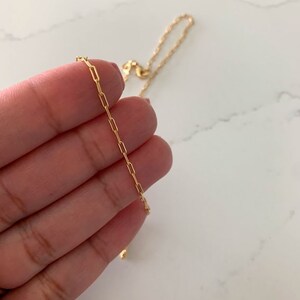May include: A gold chain necklace with a delicate, box chain design. The chain is thin and has a subtle shine.