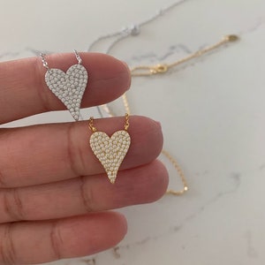 Puede incluir: Dos delicados collares con colgantes en forma de coraz&oacute;n. Ambos colgantes est&aacute;n cubiertos de peque&ntilde;as piedras brillantes. Un collar tiene una cadena y un colgante plateados, mientras que el otro tiene una cadena y un colgante dorados.