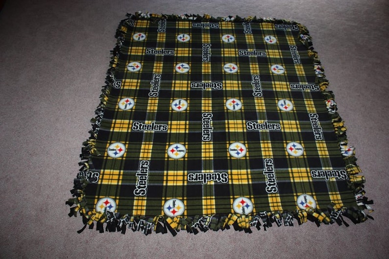 May include: A black and yellow plaid fleece blanket with the Pittsburgh Steelers logo and the word "Steelers" repeated throughout.