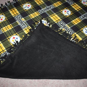 May include: A black and yellow fleece blanket with the Pittsburgh Steelers logo and the word "Steelers" repeated throughout. The blanket has a black fleece backing and a fringe border.
