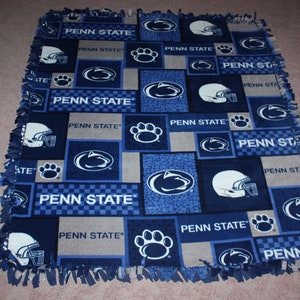 May include: A blue and gray fleece blanket with the Penn State Nittany Lions logo and the words "Penn State" repeated throughout.