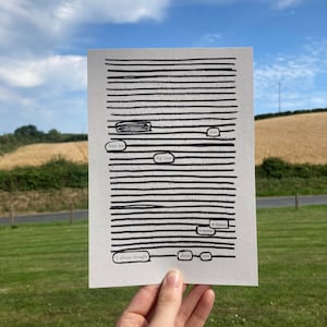 以下が含まれることがあります： 黒と白の画像で、黒い文字が強調された本が写っています。テキストは「いつも君のことを考えていた。君は僕をひどく傷つけた。本当に、僕は」と書いてあります。画像は緑の草地の背景に手の中に持たれています。