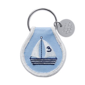May include: Blue and white sailboat keychain with a white border and the text "THREE POTATO FOUR" on a silver tag.