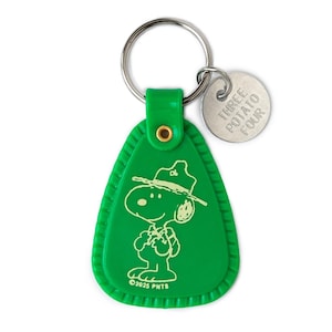 May include: Green Snoopy keychain with a silver keyring and a small circular tag. The keychain features a cartoon Snoopy character in a ranger hat. The tag reads "THREE POTATO FOUR". The bottom of the keychain reads "©2025 PNTS".