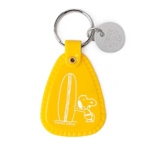 May include: Yellow Snoopy keychain with a surfboard design. The keychain features a metal ring and a small, round metal tag. The Snoopy graphic is in white, and the text "©2025 PNTS" is at the bottom.