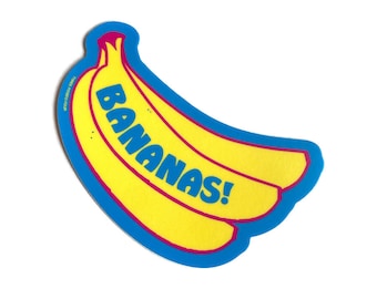 以下が含まれることがあります： 青と黄色のステッカーにバナナが2本とピンク色の「BANANAS!」の文字が書かれています。