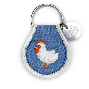 May include: Blue denim keychain with a white embroidered chicken and a silver charm that says "Triple Potato Tour".