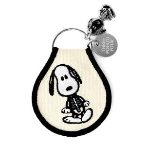 May include: A teardrop-shaped keychain featuring an embroidered white and black cartoon dog with a skeletal ribcage design on a cream-colored fabric base. It includes a silver metal ring, a small metal dog charm, and a round tag reading THREE POTATO FOUR.