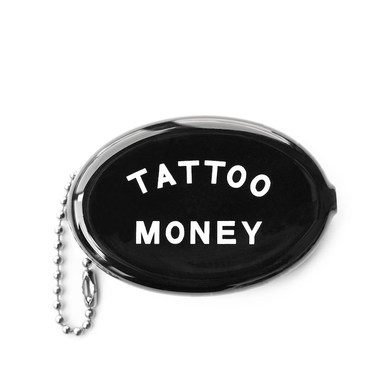 K&ouml;nnte beinhalten: Schwarze ovale M&uuml;nzb&ouml;rse mit einer silbernen Kette. Die B&ouml;rse hat die Aufschrift "TATTOO MONEY" in wei&szlig;.