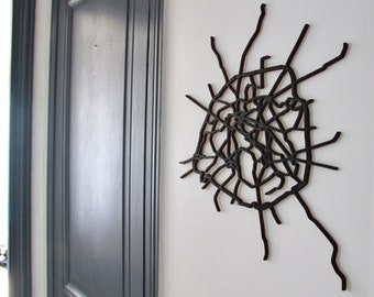 Könnte beinhalten: Ein schwarzes Wandkunststück aus Metall in Form einer Stadtkarte. Die Karte ist kompliziert und detailliert, mit vielen Linien und Kurven. Das Kunstwerk ist an einer weißen Wand montiert.