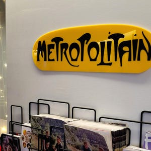 K&ouml;nnte beinhalten: Ein gelbes Schild mit dem Wort "METROPOLITAIN" in schwarzen Buchstaben.