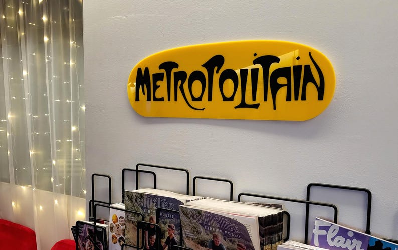 K&ouml;nnte beinhalten: Ein gelbes Schild mit dem Wort "METROPOLITAIN" in schwarzen Buchstaben.
