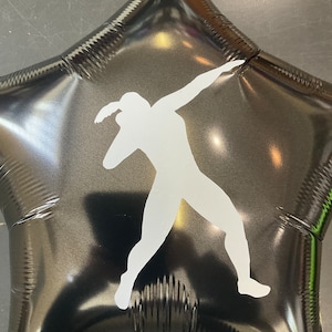 May include: Black star-shaped balloon with a white silhouette of a person in a throwing pose. The balloon has a shiny, reflective surface. The balloon is likely for a sports-themed event or celebration.