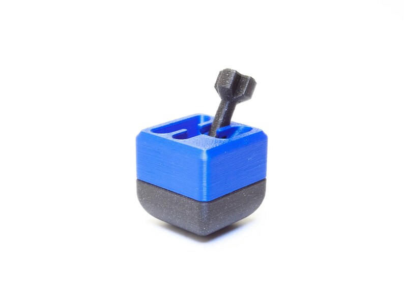 May include: A blue and black 3D printed puzzle cube with a black peg sticking out of the top.